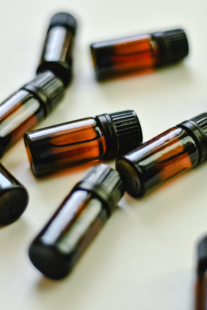 gallery-1 Collection of small amber glass bottles with black caps on a white background for product display.