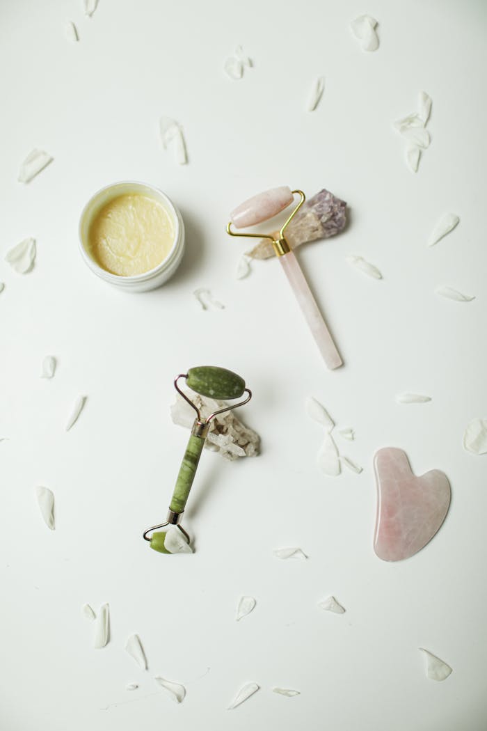 why-choose-us Flat lay of jade roller, gua sha, and cream surrounded by petals on white background. Perfect for skincare themes.